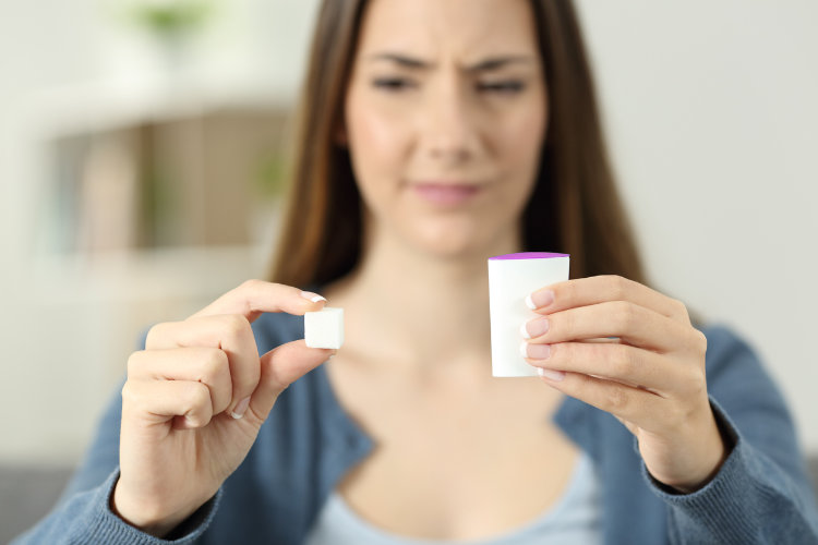 Woman comparing a sugar cube with an artificial sweetener